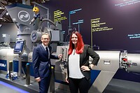 Auf der K 2025 in Halle 9: Markus Huber-Lindinger, Managing Director bei EREMA, und Sophie Pachner, R&D Manager Process Engineering bei EREMA, vor der INTAREMA® 1108 TVEplus®. Die Maschine ist mit der neuen VOLEX Technologie für hocheffiziente Entgasung und EcoGentle® für besonders schonende Plastifizierung ausgestattet.     Bildrechte: EREMA GmbH